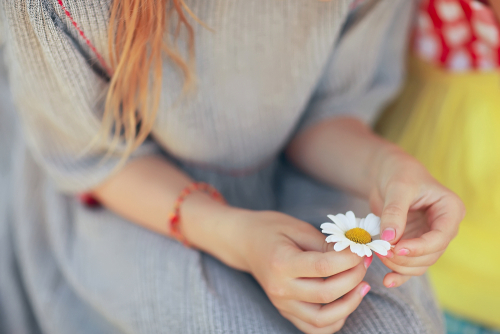 Ein Mädchen zupft die Blüten einer Blume ab und stellt dabei die Frage, liebet er mich? Das Single Dasein Spiel