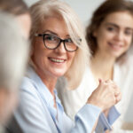 Eine blonde Frau mit Brille leitet die Kommunikation innerhalb der Gruppe.