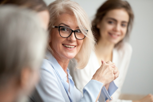 Eine blonde Frau mit Brille leitet die Kommunikation innerhalb der Gruppe.