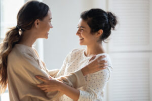 Zwei Frauen umarmen sich herzlich und lachen gemeinsam.