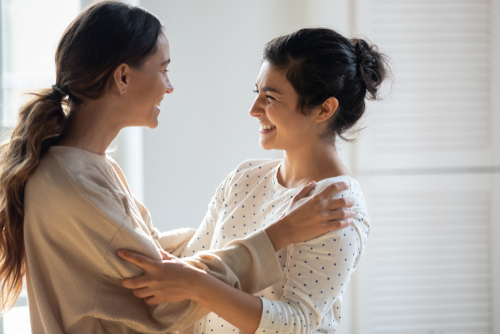 Zwei Frauen umarmen sich herzlich und lachen gemeinsam.