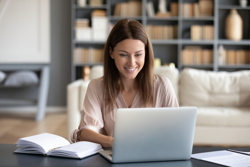 Das Bild zeigt: Frau vor dem Laptop mit Notizbuch, Website erstellen, Call, online, happy