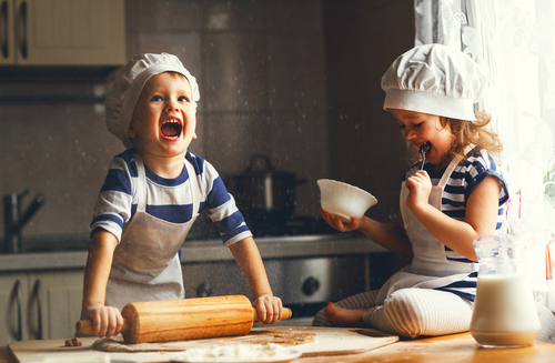 Mädchen und Junge backen fröhlich in der Küche Plätzchen