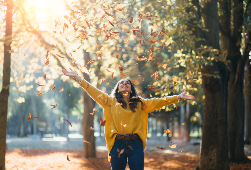 Frau, die im Herbst nach Coaching und Mentoring Stunde aus Freude Blätter wirft