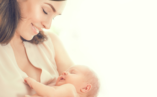 Mutter hält lächelnd das Baby im Arm