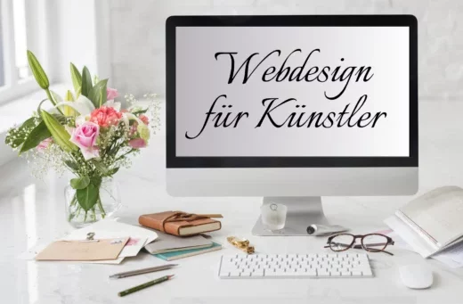 Schreibtisch mit Blumenstrauß und PC - Bildschirm auf dem steht Webdesign für Künstler