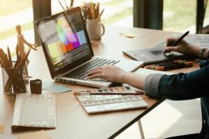 Grafikerin, die am Laptop mit Grafikdesign Ausstattung am Schreibtisch sitzt.