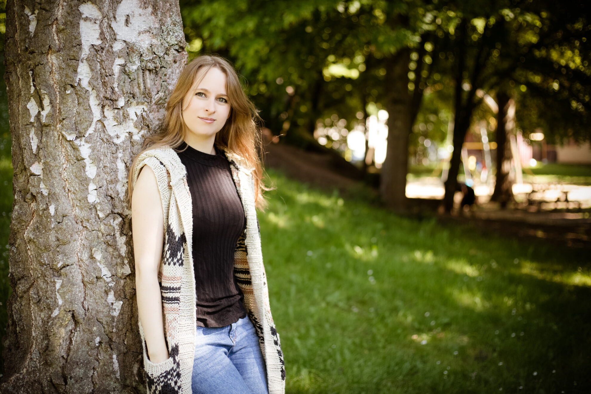 Stefanie Schmiedeberg steht in der Natur gegen einen Baum gelehnt