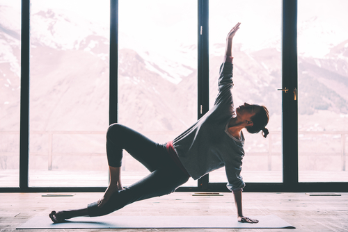 Frau trainiert und macht Yoga. Sie trainiert mit dem eigenen Körpergewicht.
