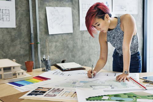 Frau steht am Schreibtisch und zeichnet - Architektur Bilder .