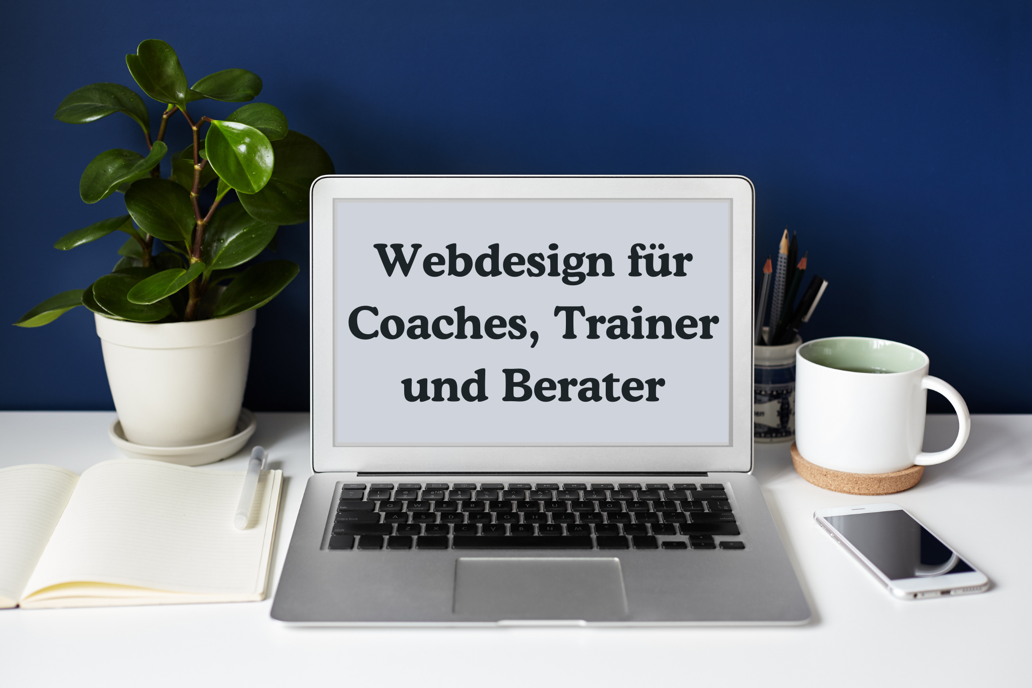 Arbeitsplatz mit Schreibtisch mit Notebook Bildschirm auf dem steht Webdesign für Coaches