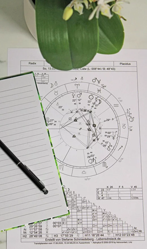 Astrologie Horoskop Radix, eine Orchidee-Blume und ein Block mit Stift