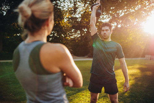 Personal Trainerin trainiert Mann. Kettlebell Training Outdoor