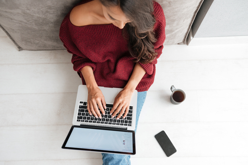 Frau sitzt am Laptop vor Website und tippt auf der Tastatur