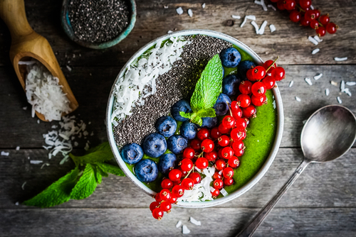Grüner Smoothie Schüssel mit Beeren auf Holzhintergrund